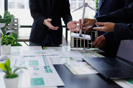 Business people discussing sustainable energy solutions with wind turbine and solar panel models during a meeting