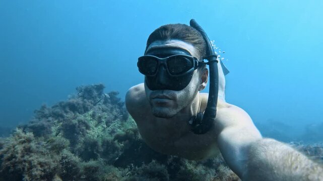 Man freediving underwater in blue sea