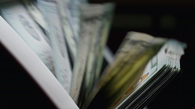 Close-up of US dollar banknotes counted by a cash counting machine. Perfect for currency exchange, international finance, banking and money transfer themes.