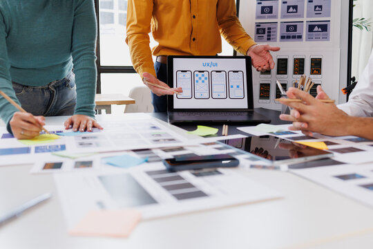 Ui ux designers collaborating on app development, creating wireframes and user interface prototypes on laptop and paper