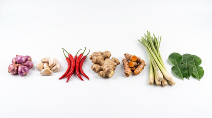 Fototapeta premium Spices and fresh herbs including ginger turmeric chili garlic lemongrass and lime leaves arranged in a neat row isolated white
