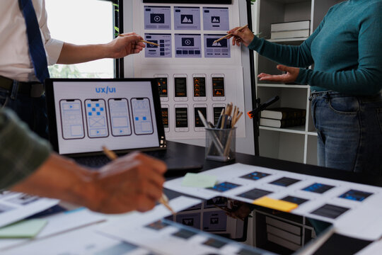 Ux ui designers collaborating on mobile application wireframes and user interface layouts, discussing web development concepts