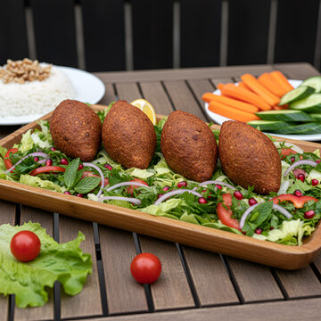 Middle eastern kibbeh fried meat croquettes on fresh vegetable salad platter