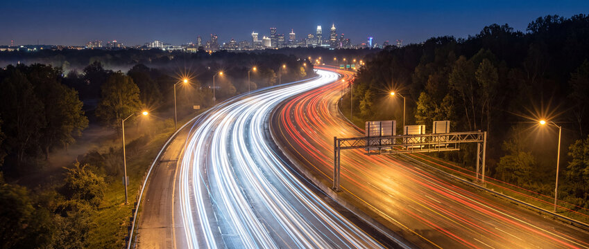 Light trails on highway to city skyline at night reveal long exposure traffic streaks with red and white lights for modern urban transportation and logistics concepts