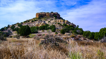 Fototapeta premium A scenic natural landscape of Oklahoma, USA, featuring a massive rocky outcrop composed of layered sedimentary rock rising above the surrounding prairie