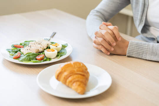 Ketogenic, Low carb, Intermittent Fasting, diet concept. Asian woman, girl confused choose, choice eat food for good healthy, between croissant bread and green salad plate. Temptation of loss weight.