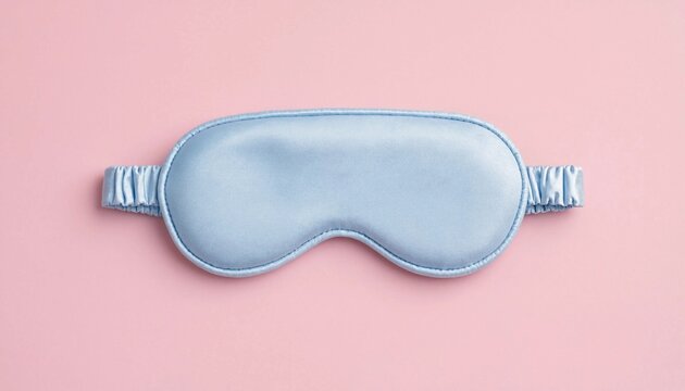 A soft blue silk sleep mask isolated on a pink pastel background for peaceful rest and relaxation