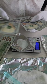 Persons weigh white powder on an electronic scale. Drug dealer pack up a dose of drugs