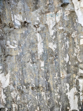 Peeling paint on a weathered wall reveals layers of aged textures and colors