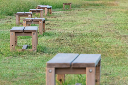 Wooden Benches Aligned in a Row on Green Grass in Public Park in Japan