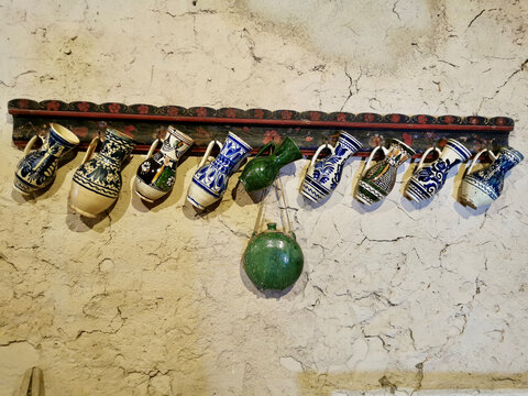 Traditional painted ceramic pitchers hanging on rustic wall