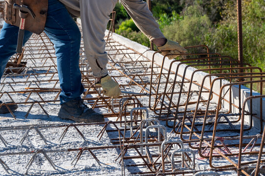 Close-up of construction worker tying steel rebar stirrups on bridge structure