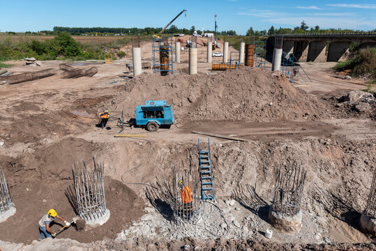 Wide panoramic view of bridge foundation construction site with concrete pillars and heavy machinery
