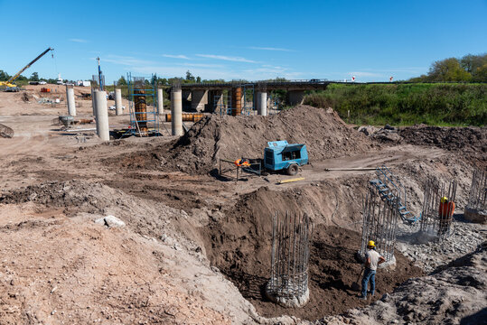 Wide panoramic view of bridge foundation construction site with concrete pillars and heavy machinery