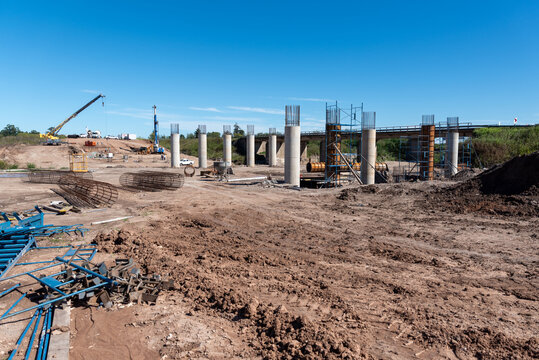 Wide panoramic view of bridge foundation construction site with concrete pillars and heavy machinery