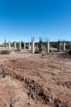 Wide panoramic view of bridge foundation construction site with concrete pillars and heavy machinery
