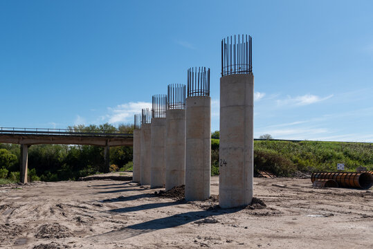 Row of concrete bridge piers with exposed rebar alignment at construction site