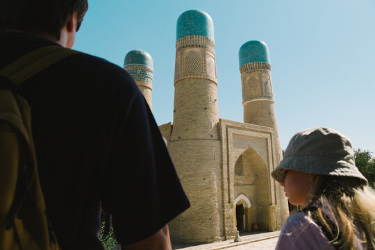 A man and a girl standing and looking at the historic Chor Minor.