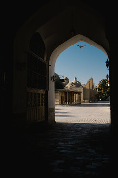 Dark archway framing a view of historic domed buildings in Bukhara.