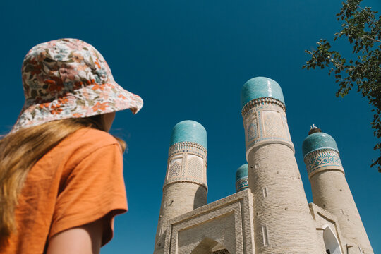 Girl looking at the historic Chor Minor building in Bukhara.