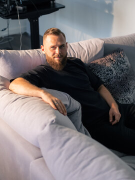 Confident man is sitting on couch at home 