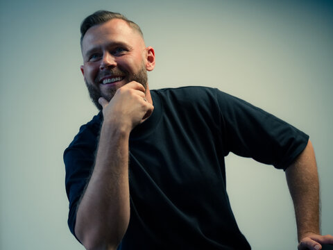Man Smiling While Resting His Chin on His Hand in a Studio