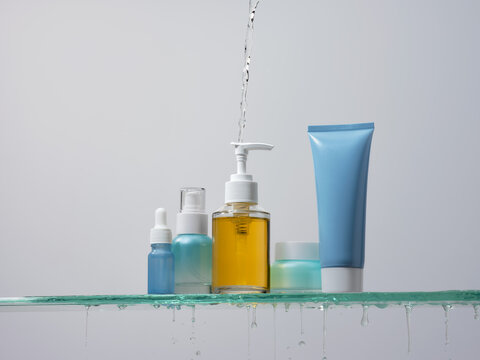 Skincare products arranged on a glass shelf with water pouring