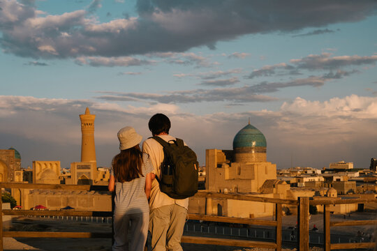 Father and daughter overlooking the Bukhara skyline at sunset.