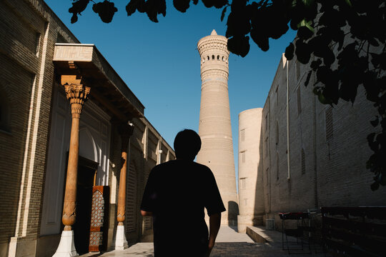 Silhouette of a person looking at a historic brick minaret.