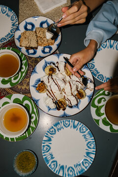 People sharing a banana and cream dessert at a table.