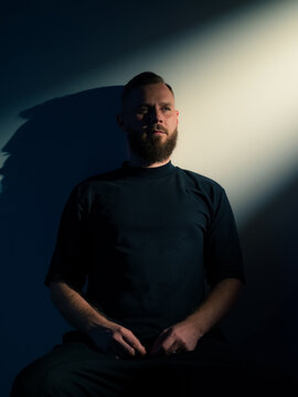 Man sitting in light against white wall 