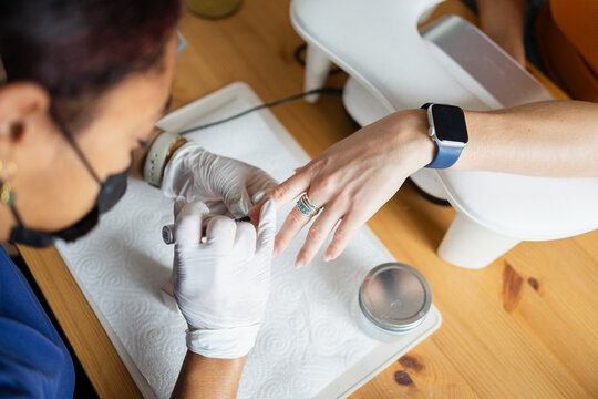 Nail technician painting a client's nails blue