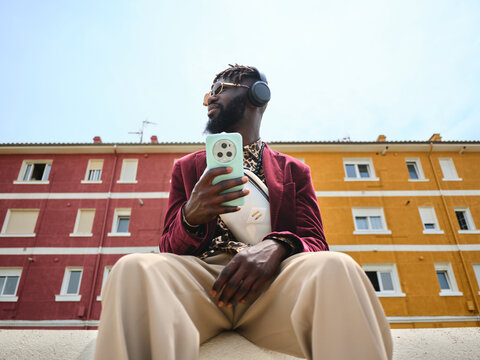 Black man holding smartphone listening music outdoors
