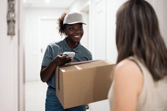 Delivery professional smiling while handing packages to customer