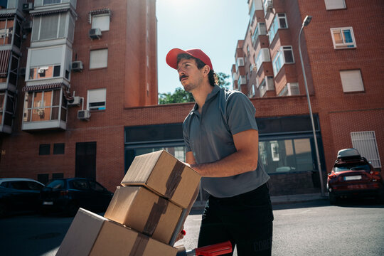 Delivery man pushing packages on hand truck