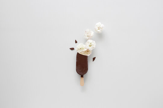 Close-up of a chocolate covered vanilla ice cream lolly with conceptual ice cream made of flowers