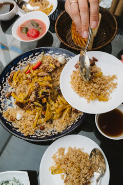 Person serving traditional plov from a large blue plate.