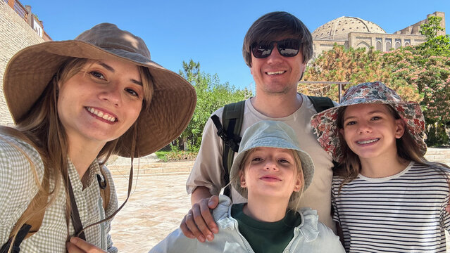 Family of four taking a selfie in a historic city square in Bukhara