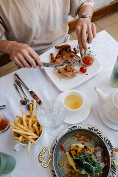 Person cutting roasted chicken at a restaurant table.