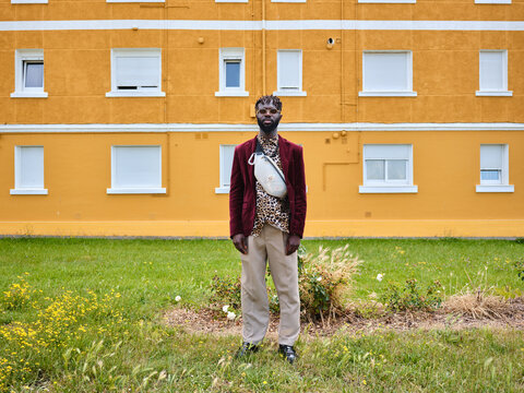 Stylish man posing against yellow urban building