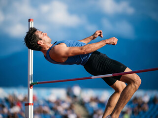 Fototapeta premium High Jumper Athlete Clearing Horizontal Bar During Track Competition