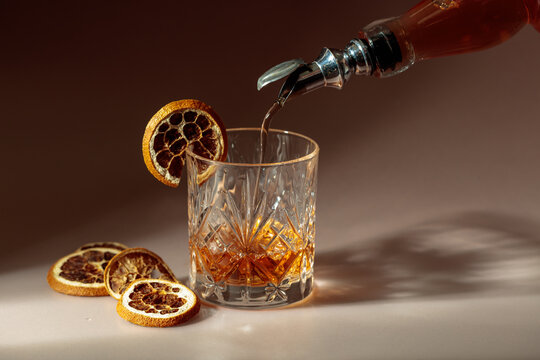 Whiskey is poured into a in crystal glass garnished with dried orange slices.