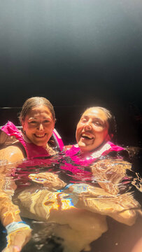 Diverse women swimming in cenote wearing life jackets