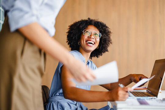 Woman Smiles While Working at a Desk in a Modern Office Space