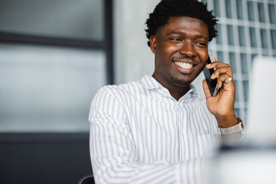 Smiling Man Talking on Phone While Sitting at a Desk