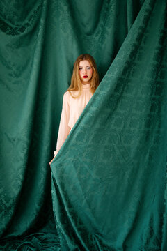 Woman behind green damask fabric 