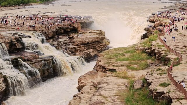 Aerial push in over a majestic raging muddy waterfall, showcasing intense fluid dynamics and raw natural power. Captured at a high frame rate. Ideal for nature and environmental projects.