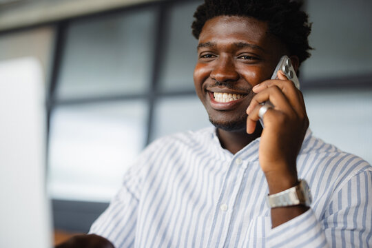 Smiling Man Talking on the Phone While Working in an Office