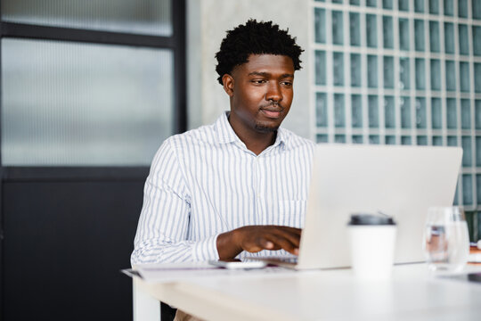 Man Works on Laptop at a Desk in a Modern Office Setting