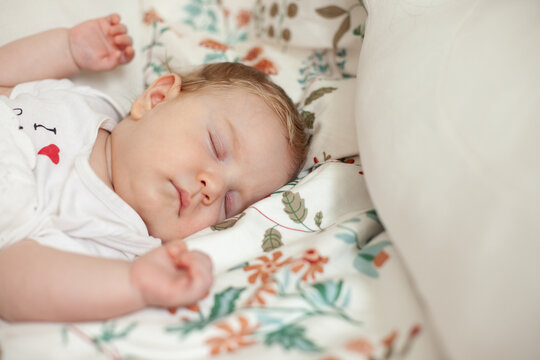 A sleeping baby nestled into a floral pillow